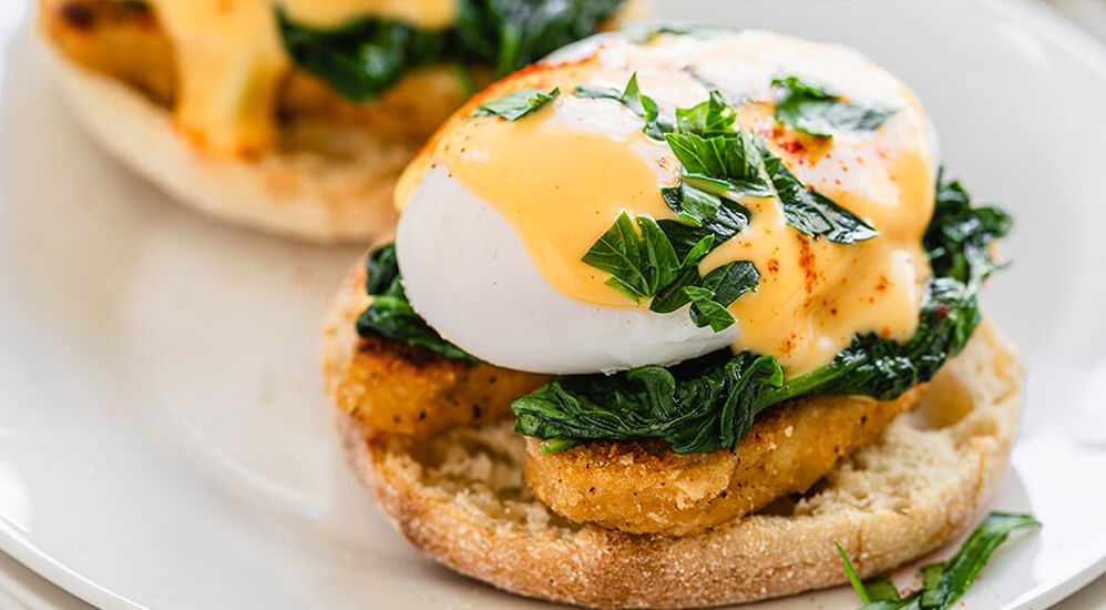 Eggs Benedict with crispy chicken and sautéed spinach